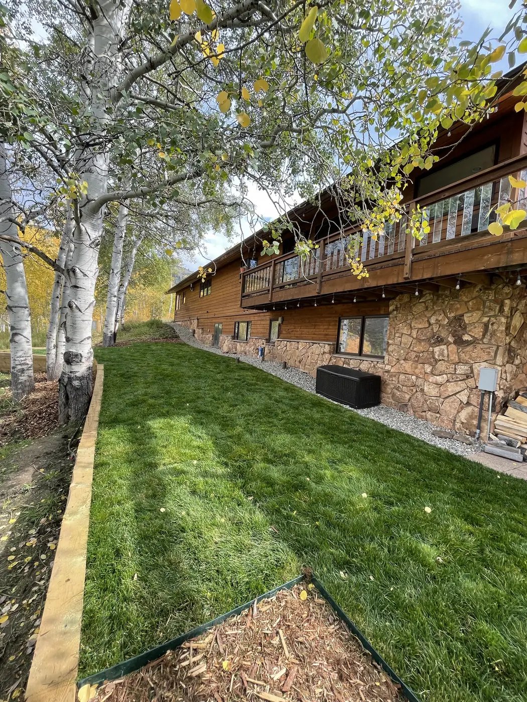 Healthy green lawn and gravel path beside a wood-sided home in Steamboat Springs
