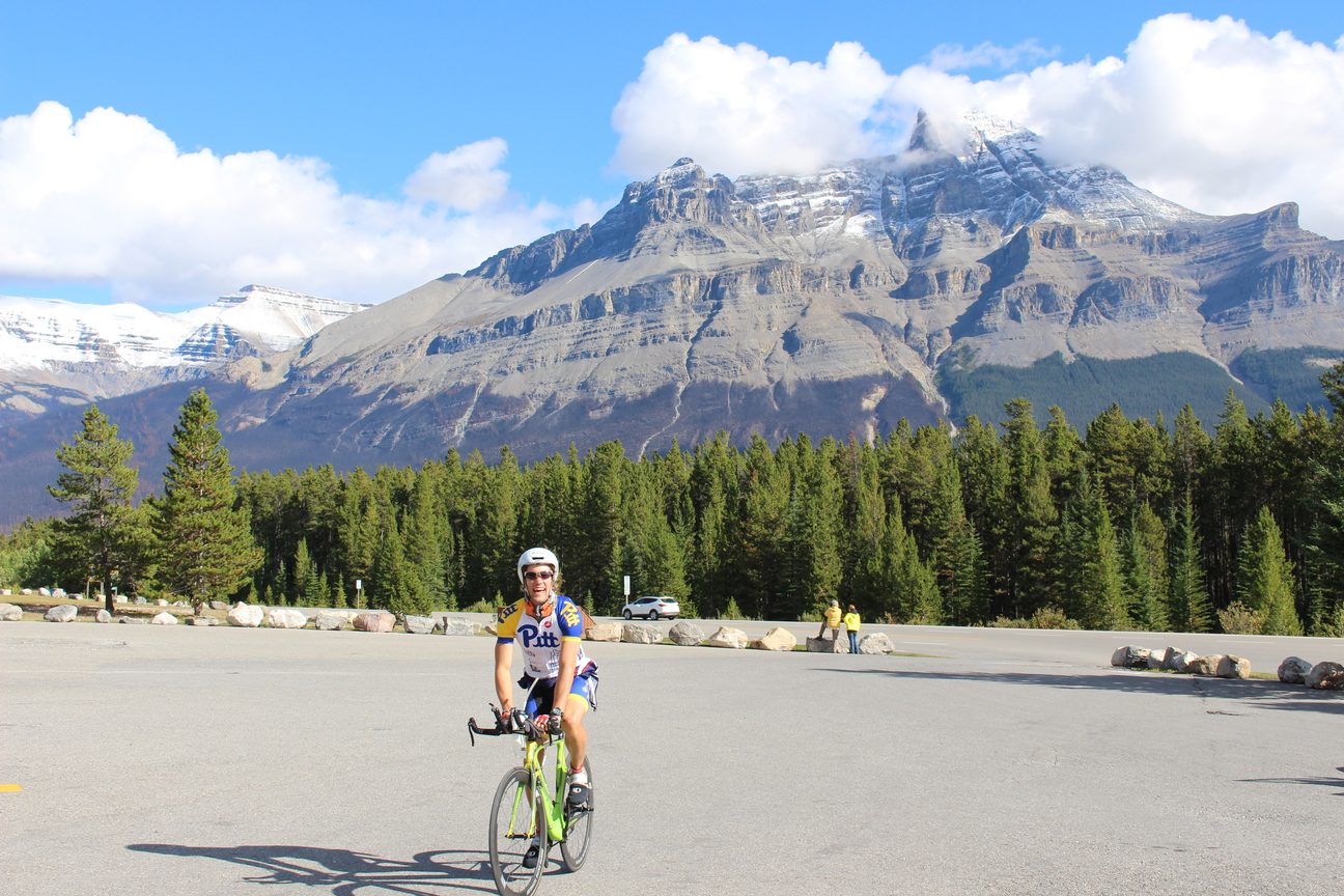 A rider on a bike in a large parking area with Mount Murchison rising behind a line of trees