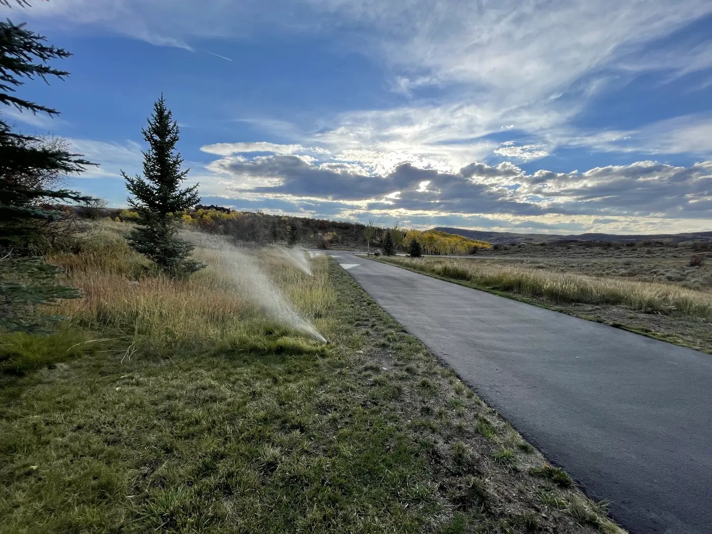 Sprinklers watering a lawn at golden hour with mountain views